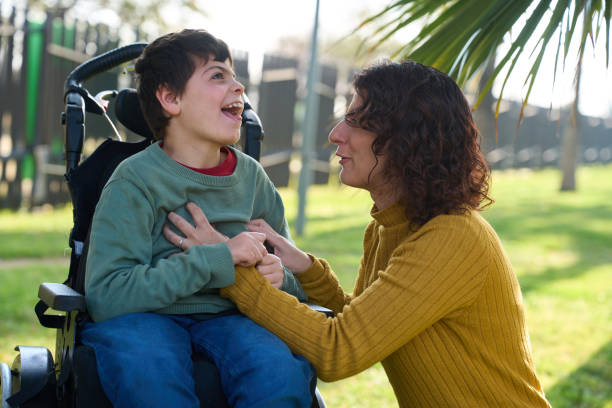 istock Happy disabled child smiling with mother in a park 2200224783