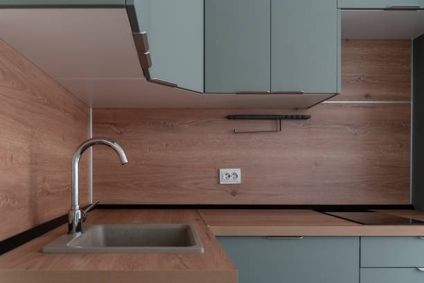 istock Modern built-in kitchen in minimalist style. blue kitchen unit, wooden countertop and kitchen backsplash. steel faucet in close-up in the foreground in the kitchen. built-in oven and microwave. 2200224820