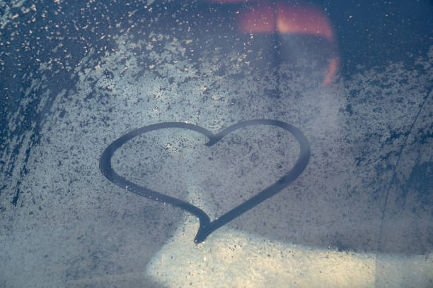 Valentine's Day concept: hand-drawn heart pattern on a frozen car windshield. Hand drawn heart shape on windshield of the car. Love symbol. Romantic background. A frozen windshield with a heart.