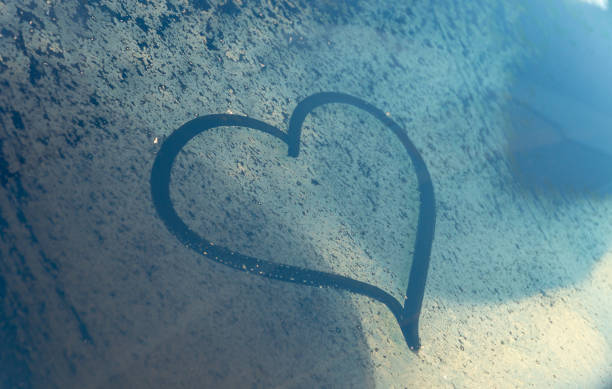 istock Valentine's Day concept: hand-drawn heart pattern on a frozen car windshield. Hand drawn heart shape on windshield of the car. Love symbol. 2200226134