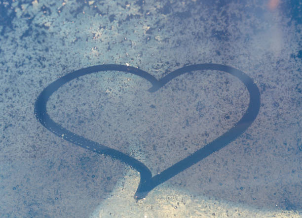 istock Valentine's Day concept: hand-drawn heart pattern on a frozen car windshield. Hand drawn heart shape on windshield of the car. Love symbol. 2200226136