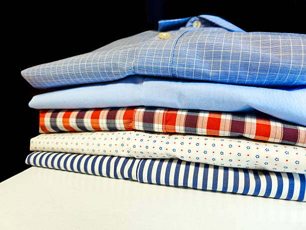 istock close-up of a stack of neatly folded clothing textiles mens button down shirts. 2200227175