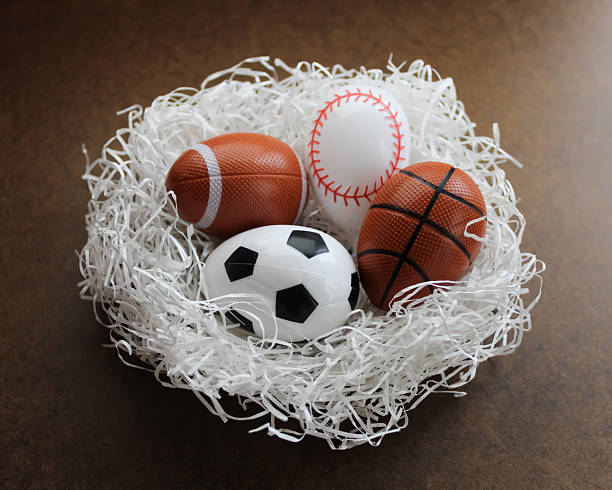istock abstract nest with sports themed Easter eggs spring backdrop graphic element eggs soccer football baseball basketball on white grass isolated on dark background 2200229897