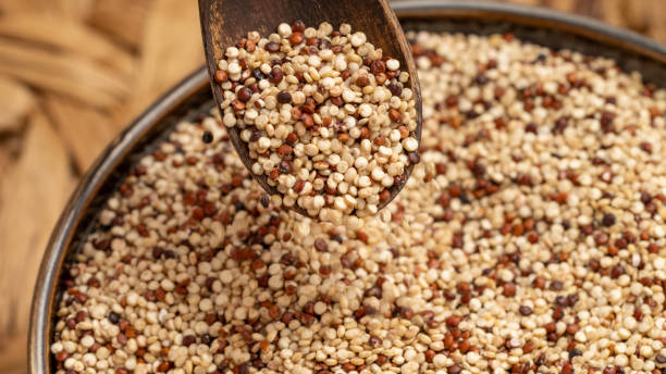 istock Wooden Spoon Pouring Mixed Quinoa Seeds into a Bowl 2200231649