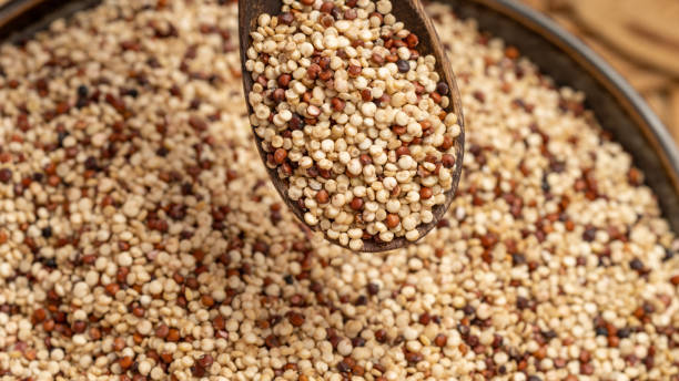 istock Wooden Spoon Pouring Mixed Quinoa Seeds into a Bowl 2200231668