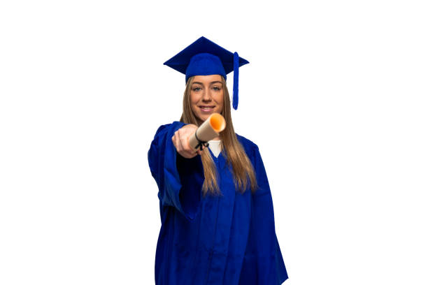 Young graduate student wearing blue gown and mortarboard, proudly showing her diploma to the camera, celebrating her academic achievement on a white background
