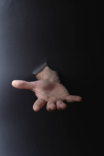 istock photo Mysterious hand emerging from darkness symbolizing assistance, reaching out for connection, support, and a helping hand amidst shadows in an enigmatic scene 2200232571