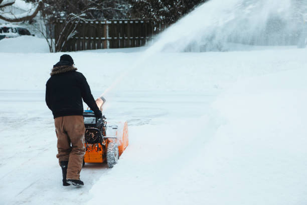 A man is removing snow from his driveway with a snowblower.
