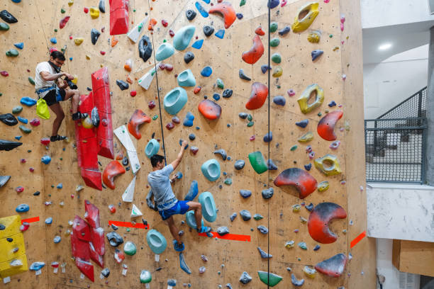 istock Two Men Rock Climbing Indoors on a Colorful Wall for Exercise 2200237083