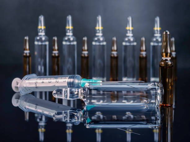 istock Ampoules with medicine and syringe on glossy black background 2200237964