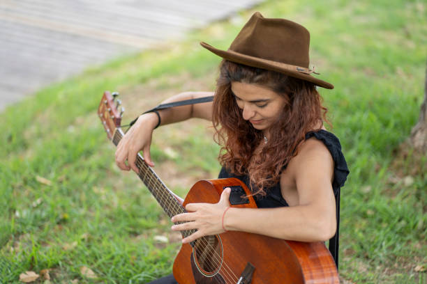 istock Female guitarist tuning her guitar 2200242376