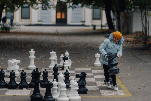 istock Girl playing giant chess in park during autumn 2200245307