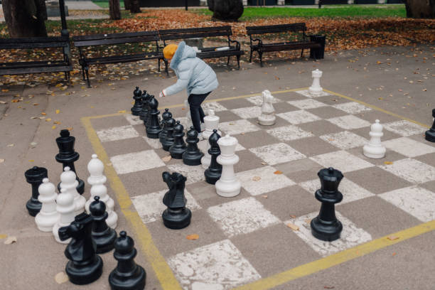 istock Child playing giant chess in the park during autumn 2200245454