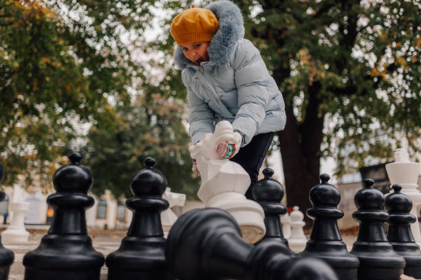istock Girl playing giant chess in park captures white knight 2200245455