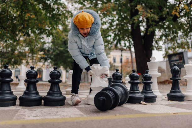Girl playing with giant chess pieces in park