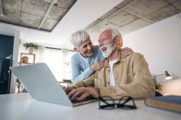 istock Happy senior couple laughing while using laptop at home 2200257471