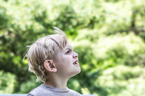 Close up of a 7 year old blonde boy looking in the distance while the wind blows his hair.