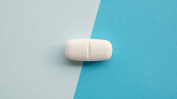 istock White medicine pill tablet on blue and white background 2200268649