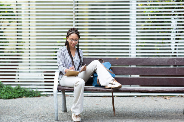 istock Beautiful african woman sitting outside taking notes in her notebook 2200268718