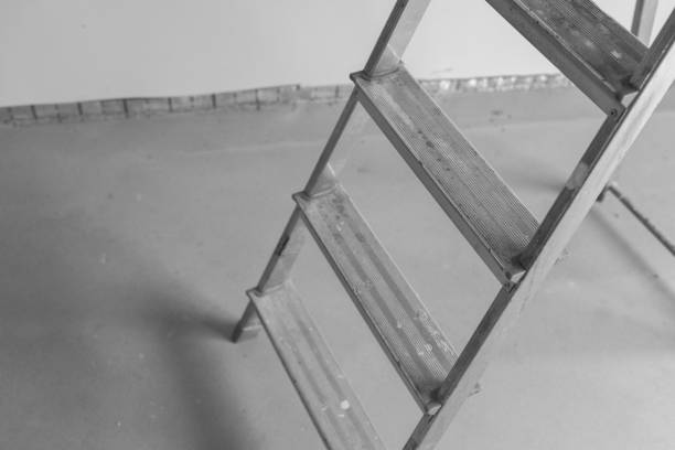 A metal ladder stands on a smooth concrete floor during a renovation task.
