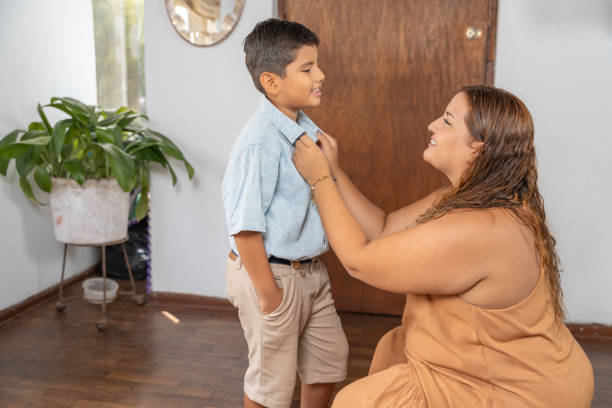 istock Caring hispanic mother adjusting her son's shirt at home 2200271187