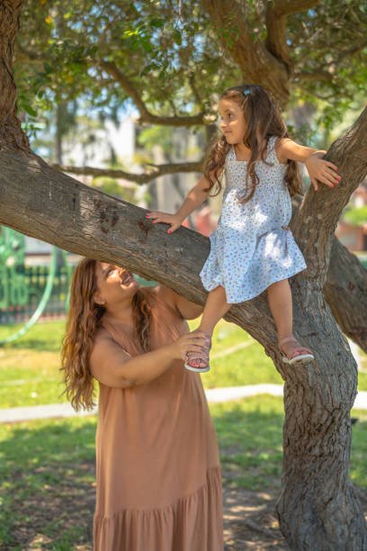 istock Mother helping daughter climbing tree in park 2200271472