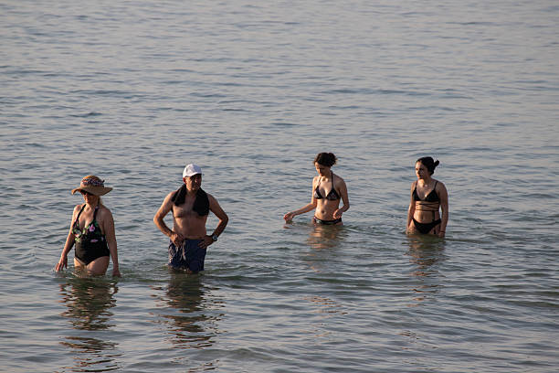 Vasto, Chieti, Italy: August 2, 2024: As the sun rises, tourists walk along the shoreline in cold seawater, savoring the refreshing ocean breeze and the peaceful beauty of the morning.