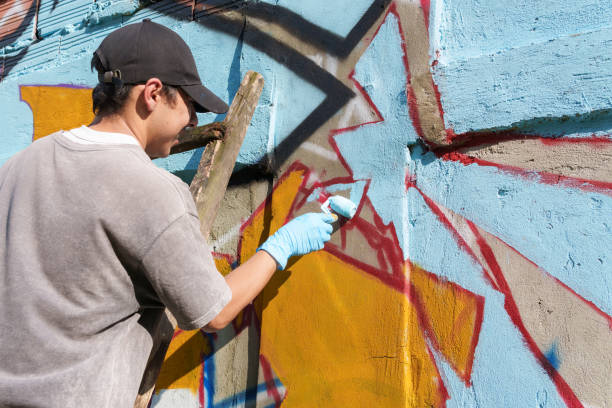 istock Graffiti artist painting colorful mural on concrete wall with paint roller 2200304309