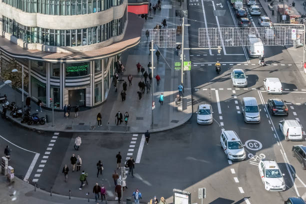 Madrid, Spain - November 30, 2021: Busy street intersection in Madrid with pedestrians walking past the iconic United Colors of Benetton store. Vehicles and pedestrians move in harmony in this bustling urban scene