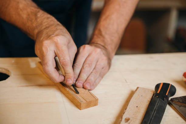 istock Close-up of carpenter hands using a chisel to mark and shape a wooden plank in a workshop. Hands expertly handling the chisel, demonstrating precision and dedication to craftsmanship 2200309477