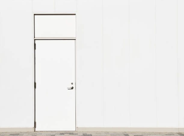istock White concrete wall with closed white metal door 2200312915