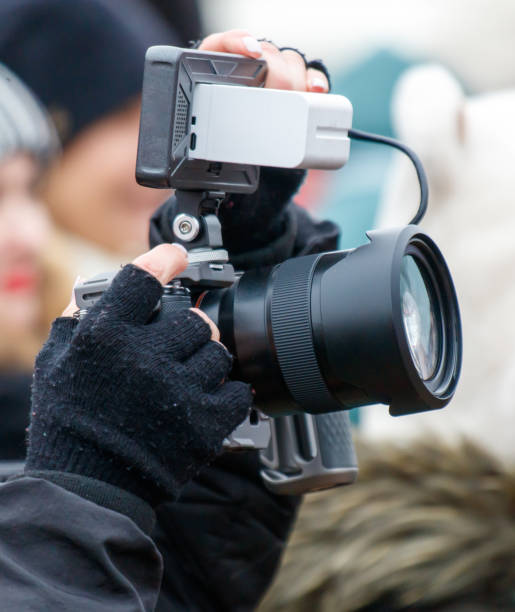 istock A person is holding a camera with a lens and a white object attached to it 2200314224