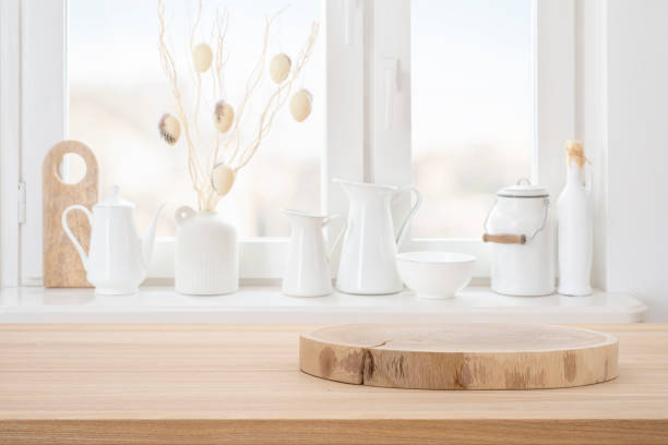 istock Wooden pedestal on kitchen table for product presentation with white kitchenware window sill interior background 2200318167