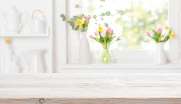 istock Empty wooden table on bright blurred interior of white kitchen window sill with colorful flowers 2200318180