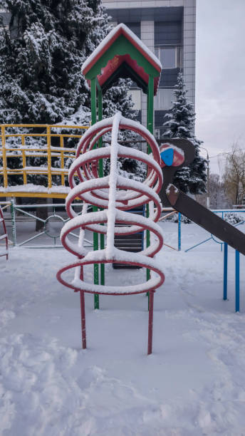 istock Children's playground covered with snow. Empty swings and slides. 2200318637