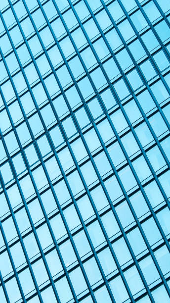 istock Abstract Grid Reflection. A close-up of a modern glass building facade, featuring a repetitive grid pattern with reflections of the sky 2200319777
