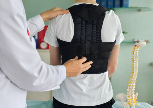 istock Health professional fitting a back support on a patient in a medical office during a consultation 2200321737