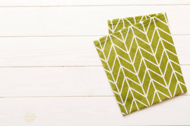 istock top view with green kitchen napkin isolated on table background. Folded cloth for mockup with copy space, Flat lay. Minimal style 2200324025