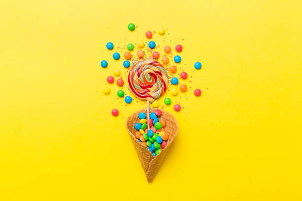 istock waffle cone full of assorted traditional candies falling out on colored background with copy space. Happy Holidays sale concept 2200324064
