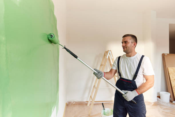 istock Happy house painter painting the wall in green. 2200324964