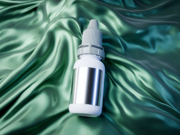 white plastic dropper bottle with a ribbed cap and reflective metallic label rests on smooth, flowing green satin fabric, combining modern aesthetics with luxury.