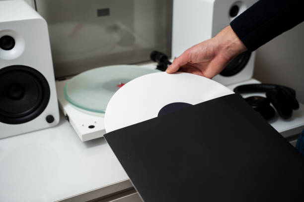 istock Vinyl LP tracks with modern needle player. Musician changes vinyl record into turntable player and speaker system. 2200338322