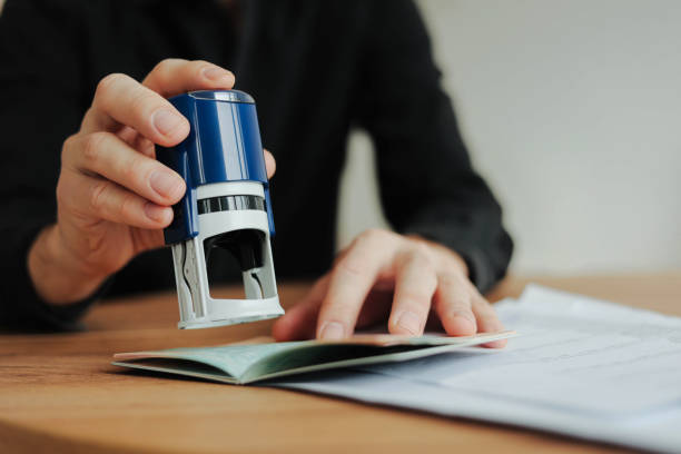 istock Man border control worker puts a stamp in the passport. Tourism, boarding control. Copy space. 2200338383