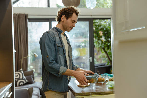 istock Young man packing food into containers 2200339374