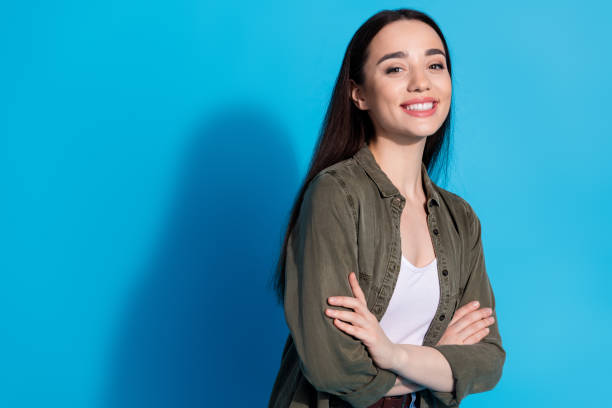 istock Charming young woman smiling against a bright blue background while standing confidently with arms crossed 2200339585
