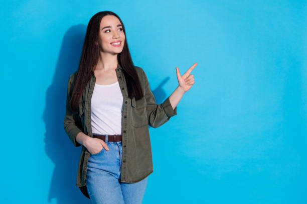 istock Young woman gestures confidently in casual attire against blue backdrop 2200340413