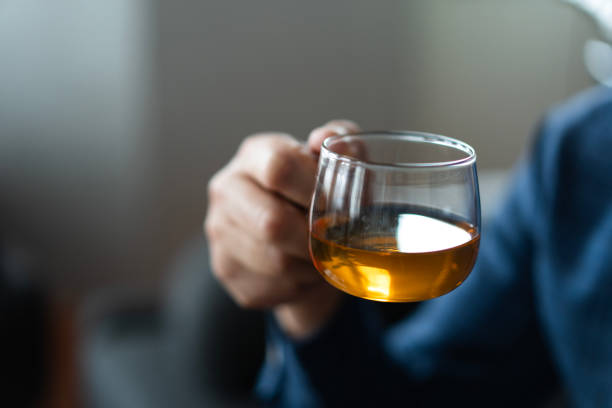 Close-up of a man holding a transparent glass cup with herbal tea