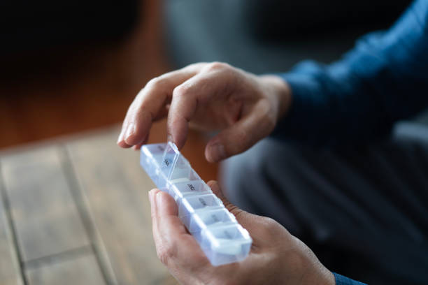 Senior man taking medication from pill organizer at home
