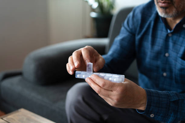 istock Senior man taking medication from pill organizer at home 2200342005