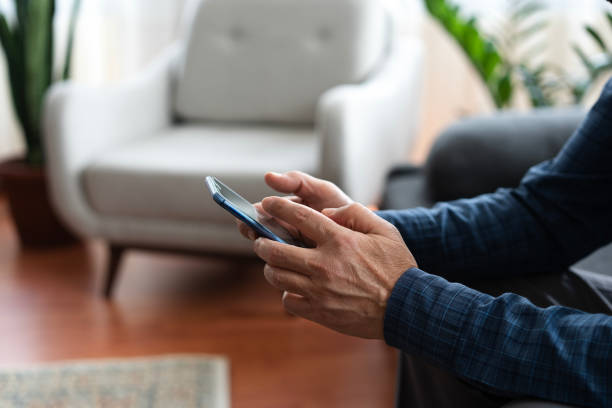 istock Senior man using smartphone at home, scrolling through social media 2200342196